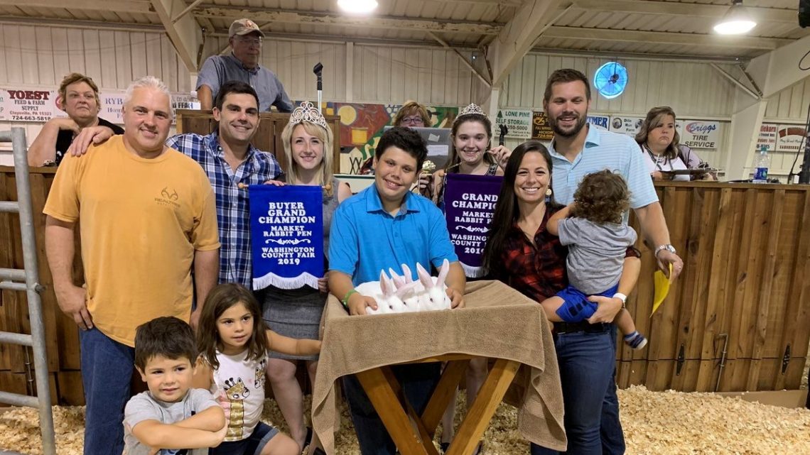 People in a barn with award winning rabbits