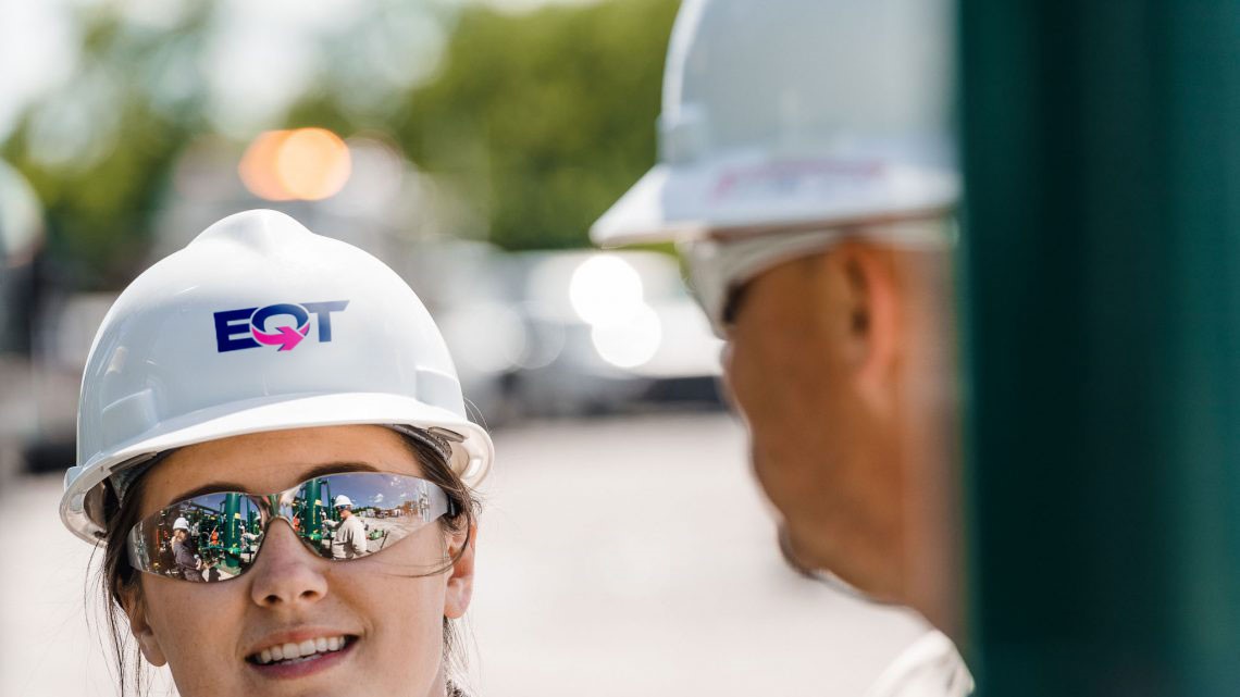Woman in EQT hardhat talking to someone on a job site